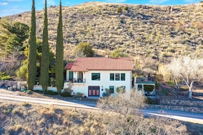 A two-story house with a red-tiled roof, a balcony, and a stone wall. - Little Daisy Historic Villa Sleeps 8 Sedona Views (Jerome)