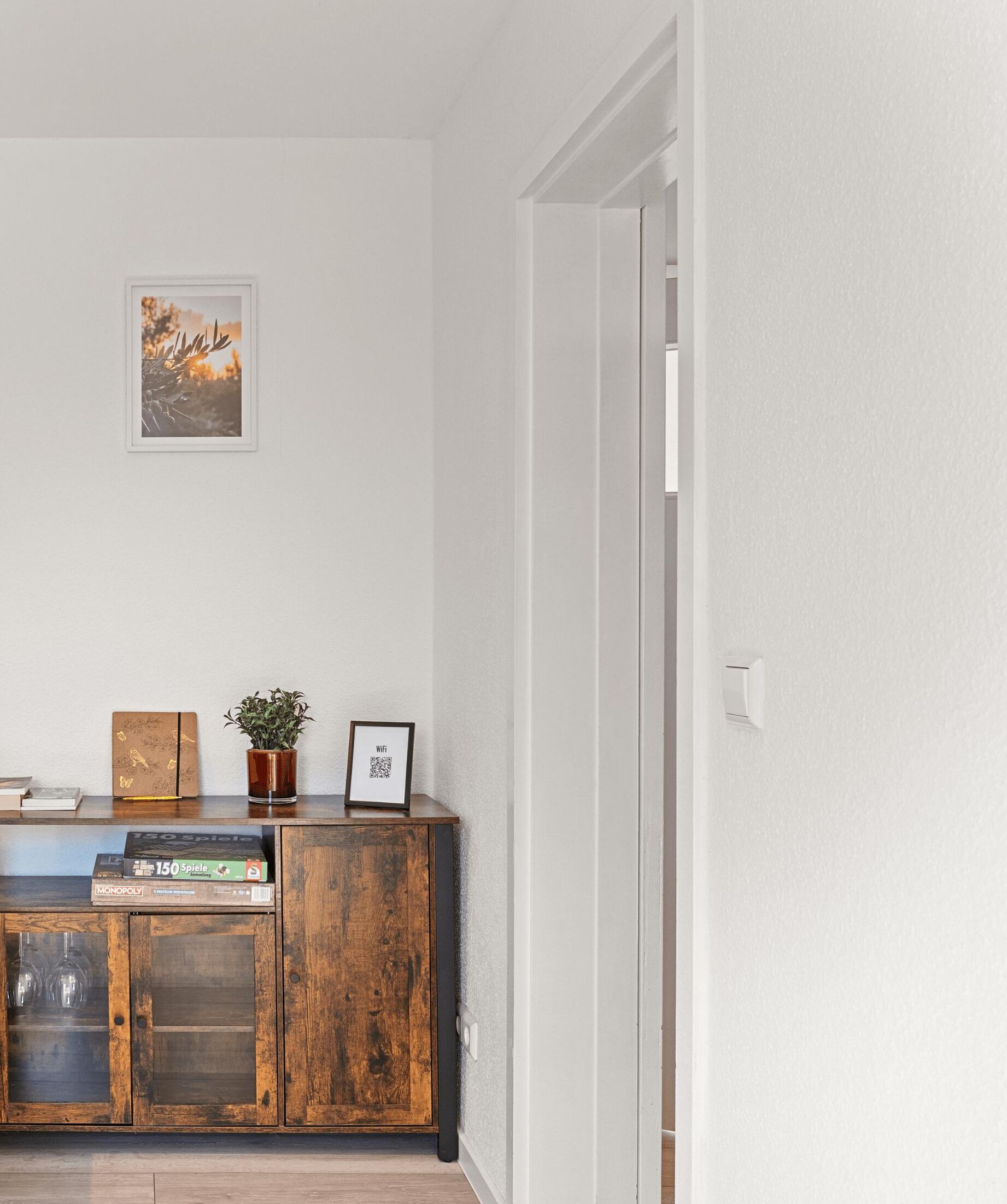 Una habitación con un armario de madera, un cuadro enmarco, una planta y un código QR en el armario.