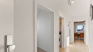 Een modern interieur met een gang die leidt naar een eethoek en keuken.