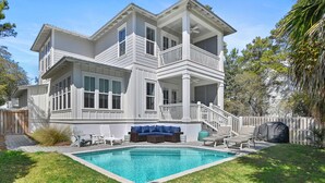 Ein zweistöckiges Haus mit Balkon, Swimmingpool und Gartenmöbeln.