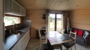 Una cocina compacta con zona de comedor, paredes de madera y vistas a través de un ventanal.
