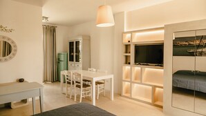 A modern hotel room with a dining area, a television, and a bed. - Villa Del Ponente Otranto (Otranto)