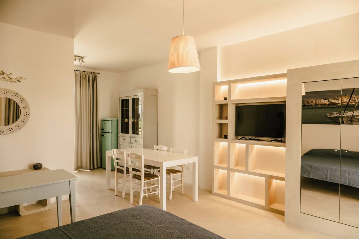 Una habitación de hotel moderna con comedor, televisor y cama.