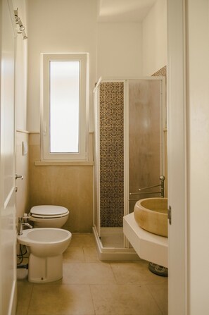 A compact bathroom with a toilet, bidet, and a shower enclosure. - Villa Del Ponente Otranto (Otranto)