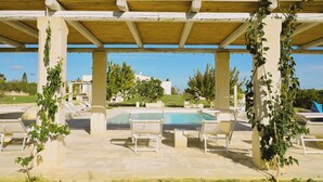 A covered outdoor area with a pool and lounge chairs. - Villa Del Ponente Otranto (Otranto)