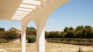 A white architectural structure with arches and a stone wall in the background. - Villa Del Ponente Otranto (Otranto)