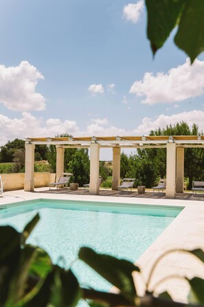 A pool area with a pergola, lounge chairs, and a clear blue sky. - Villa Del Ponente Otranto (Otranto)