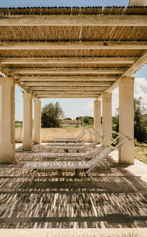 An outdoor pavilion with a bamboo roof, concrete pillars, and sun loungers. - Villa Del Ponente Otranto (Otranto)