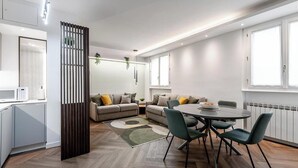 Una sala de estar moderna con un juego de sofá, una mesa de comedor con sillas y una zona de cocina con un microondas.