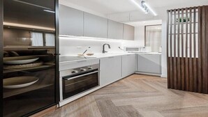 Una cocina moderna con horno empotrado, microondas y un armario de vidrio con vajilla.