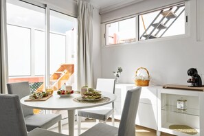 A bright, modern kitchen with a round dining table, white chairs, and a view of the outside through large windows. - City Centre Retreat by Homie (Funchal)