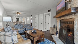 A living room with a fireplace, sofas, a coffee table, and a ceiling fan. - Hilltop Paradise (Gatlinburg)