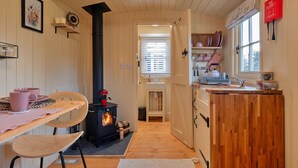 A cozy kitchen with a wood-burning stove, wooden cabinets, and a dining area with a table and chairs.