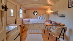 A cozy bedroom with a bed, bedside table, and a small desk with a chair.
