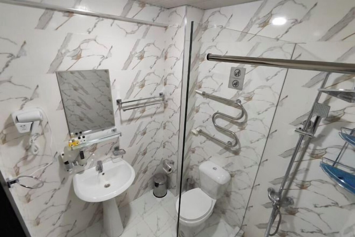 A bathroom with a glass partition, a white sink, a toilet, and a shower area.