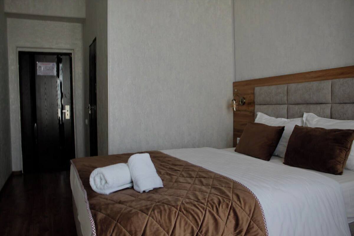 A hotel room with a large bed, a wooden headboard, and a door with a sign.