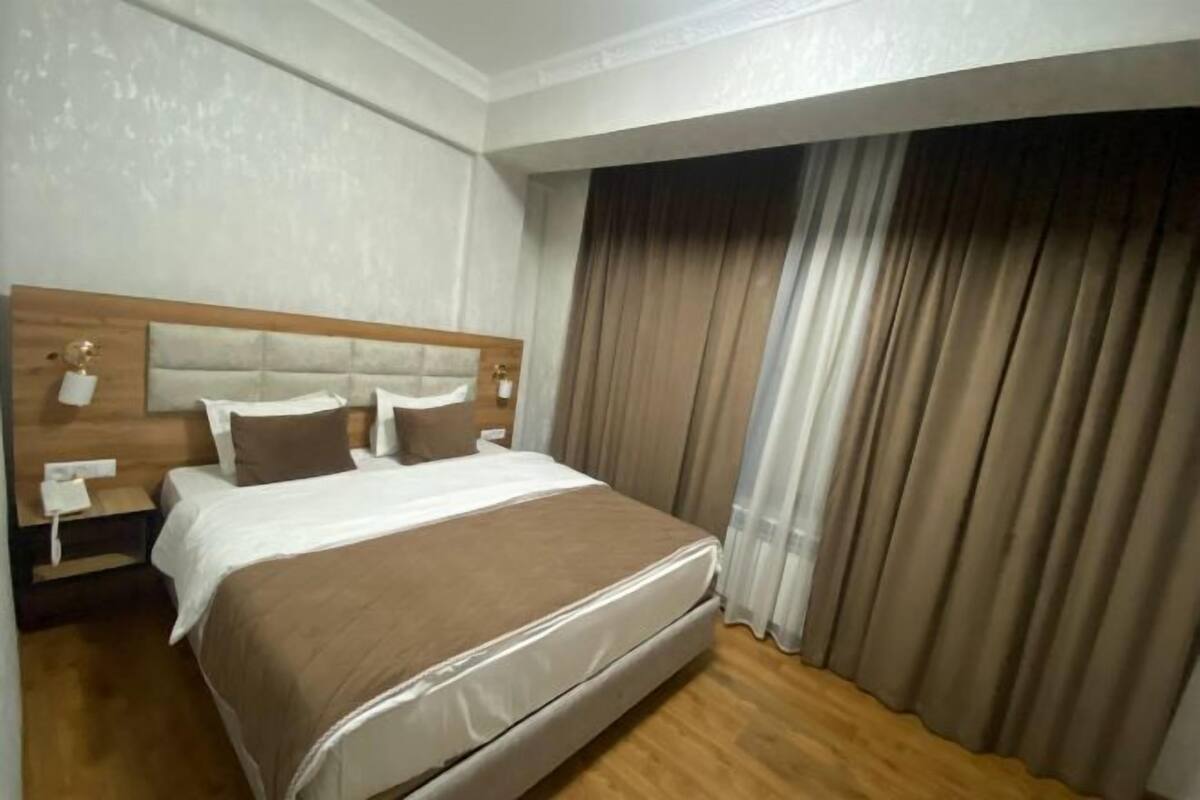 A hotel room with a large bed, wooden headboard, and a nightstand with a lamp.