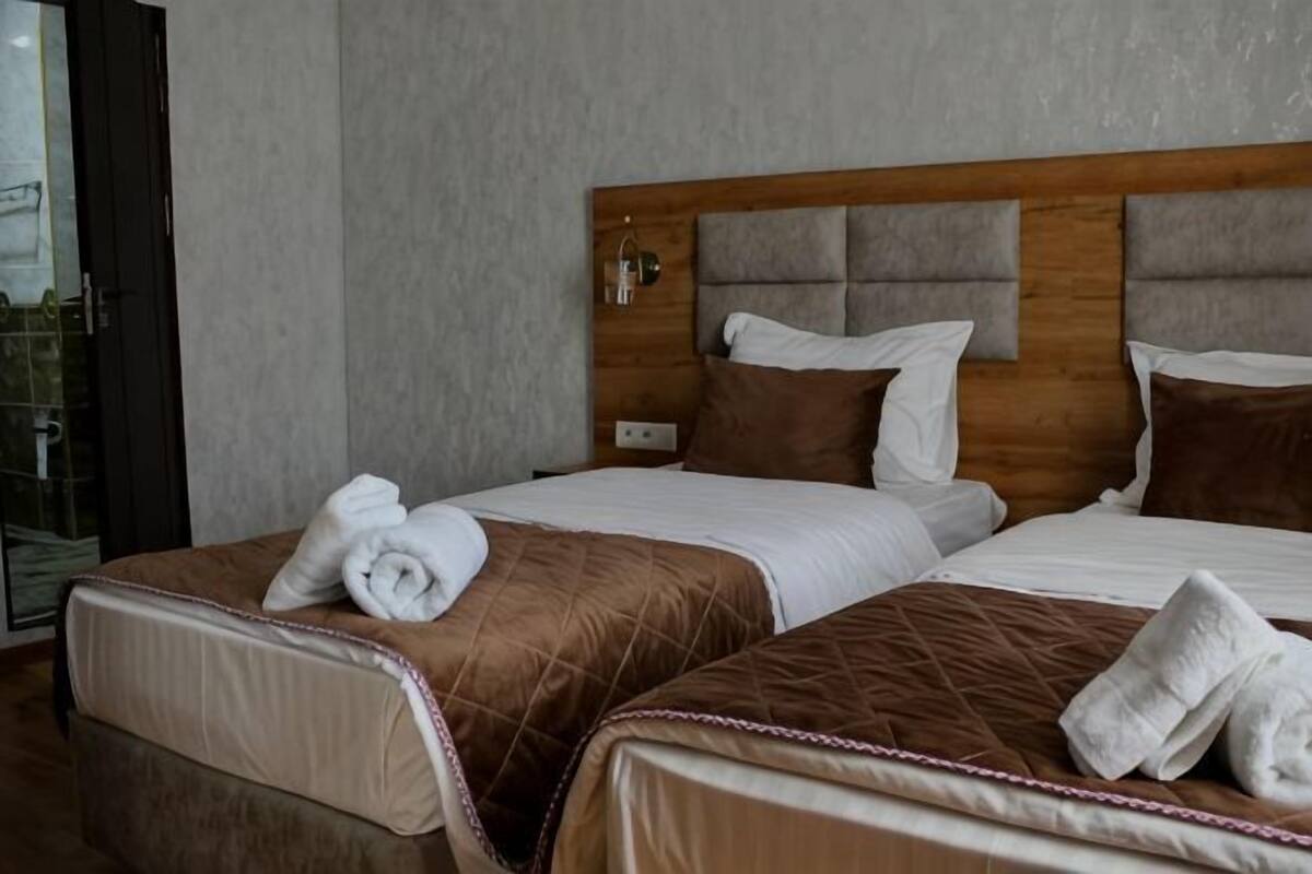 A hotel room with two beds, a wooden headboard, and a glass door leading to a balcony.