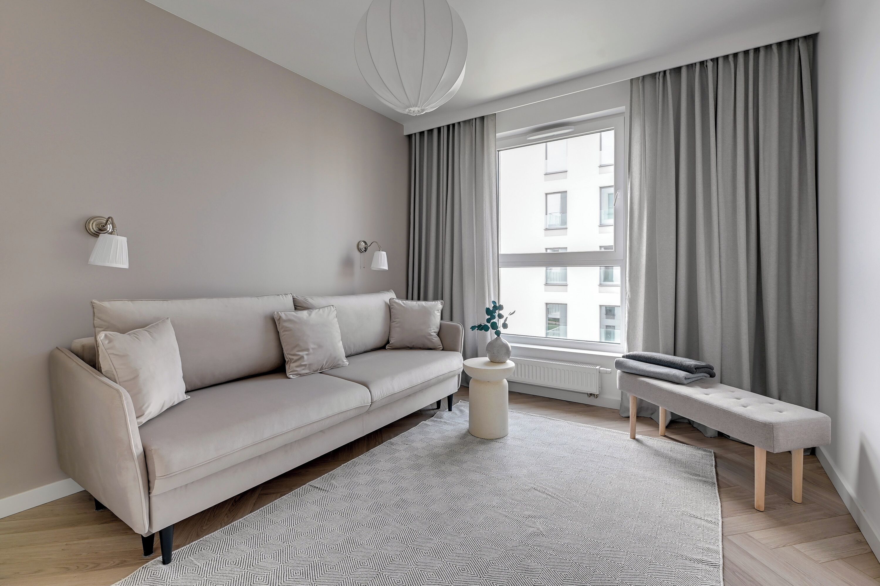 A modern living room with a beige sofa, a round side table, and a bench.