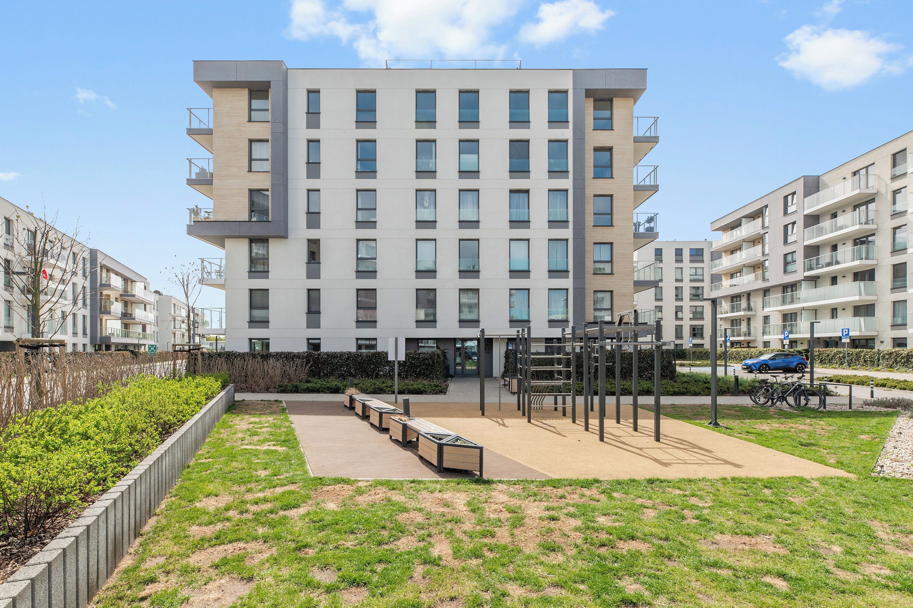 A modern multi-story residential building with a flat roof, large windows, and balconies.