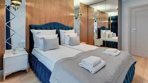 A modern hotel room with a large bed, a nightstand, a mirror, and a wooden accent wall. - Seaside Przystań Letnica by Downtown Apartments (Gdansk)
