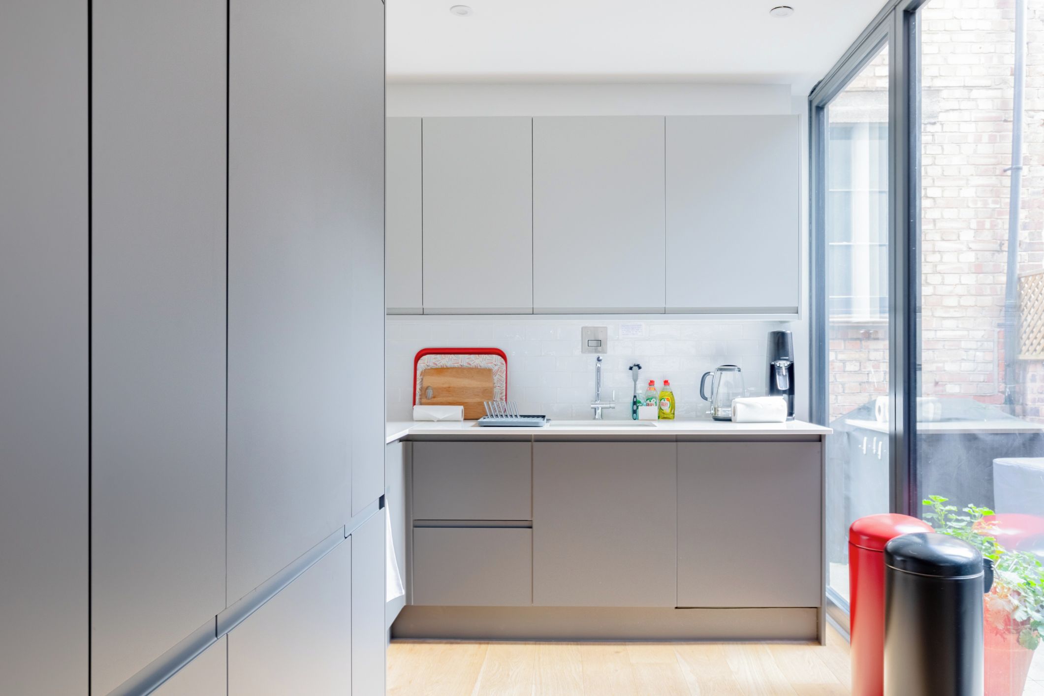 Una cocina moderna con armarios grises, encimera de madera y un ventanal grande.
