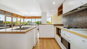A modern kitchen with a large island, built-in appliances, and a view of the outdoors. - Ocean Breeze - Retreat in Torquay, Sleeps 11! (Torquay)