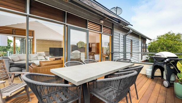 A modern outdoor deck with a dining table and chairs, a barbecue grill, and a large sliding glass door leading to an interior living space. - Ocean Breeze - Retreat in Torquay, Sleeps 11! (Torquay)
