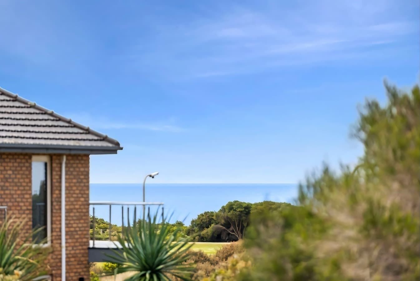 A house with a brick exterior, a tiled roof, and a view of the ocean.
