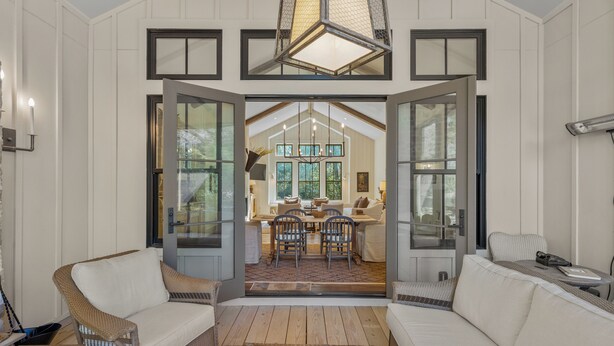 A spacious entryway with a dining area, featuring a large chandelier, wicker furniture, and a view into the dining room. - Hemlock Mist: Modern Lakeside Home w/  Screened Porch, Kayak (Highlands)