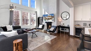 A spacious living room with a fireplace, a television, and a kitchen area. - Moose Mgmt at Retreat 1157: Gourmet Kitchen, King Bed, 85" TV, Fast Wifi (Park City)