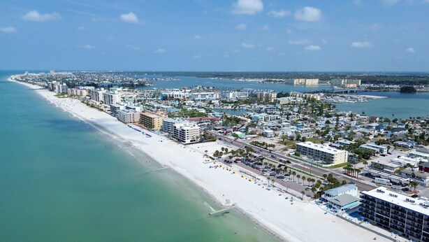 A coastal cityscape with a long sandy beach, dense urban development, and a marina.