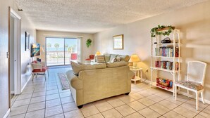 A living room with a beige sofa, a white bookshelf, and a red chair.
