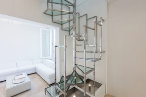 Ein modernes Interieur mit einer Glaswendeltreppe, weißen Möbeln und einem Glastisch.
