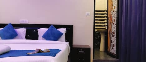 A hotel room with a bed, a nightstand, a bathroom with a sink and mirror, and a door with a curtain.