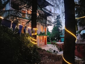 Un edificio con balcón, rodeado de árboles y luces colgantes.