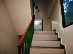 Een trap met een groene leuning die naar een deur leidt.