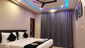 A bedroom with a bed, a ceiling fan, and a window with curtains.