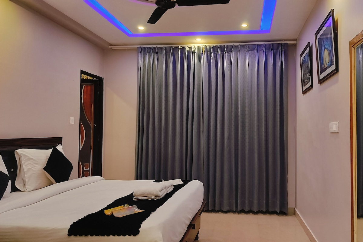 Una habitación de hotel con cama, cortinas, ventilador de techo e iluminación empotrada.