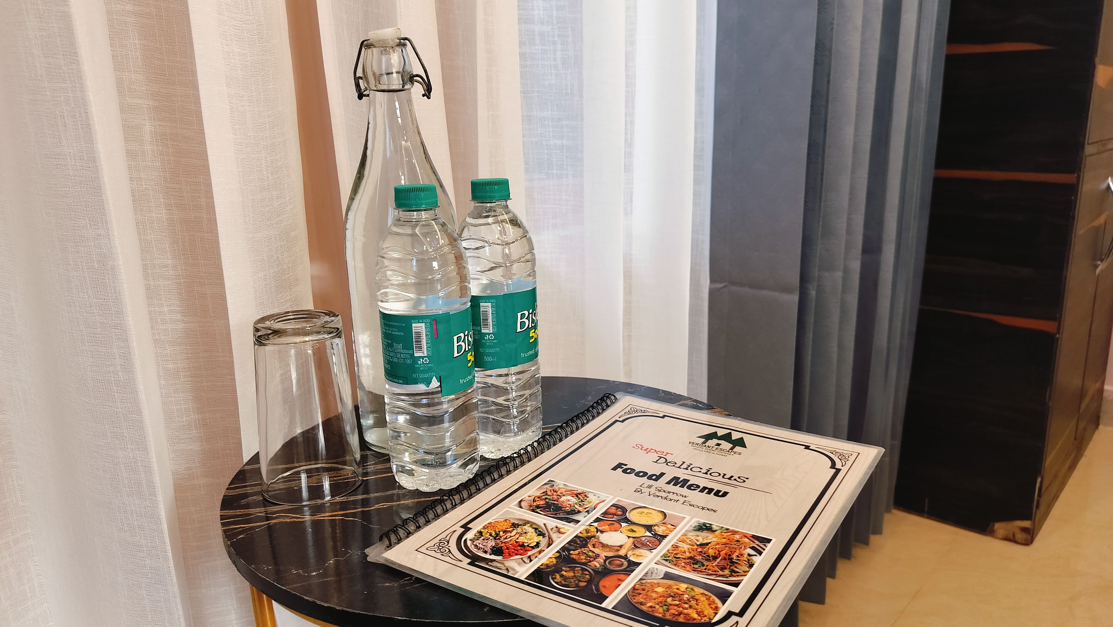 A table with a menu, two water bottles, and a glass.