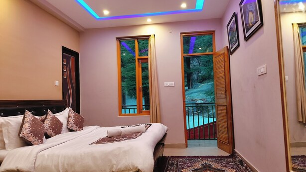 Een slaapkamer met een bed, een raam en uitzicht op een bos.