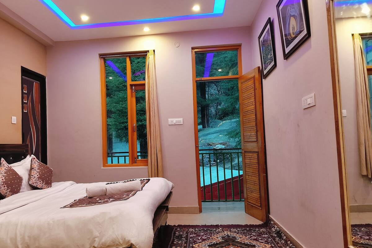 Un dormitorio con cama, ventana y vista a un bosque.