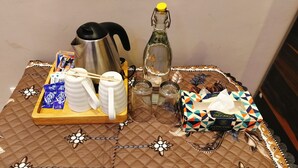 Een tafel met een koffiezetapparaat, theepotten, een fles, glazen en zakdoekjes.