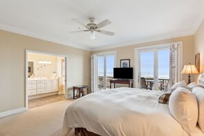 Une chambre dotée d’un grand lit, d’un ventilateur de plafond, d’une télévision et d’un balcon offrant une vue sur la plage.