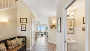 Un pasillo con un banco, cuadros enmarcados y vistas a una habitación con ventana.