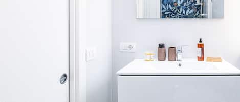 A modern bathroom with a white vanity, a mirror, and a shower with a floral shower curtain.