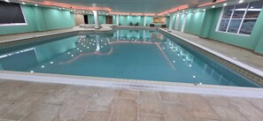 An indoor swimming pool with a tiled floor, surrounded by walls with windows and a ceiling with recessed lighting. - Hustyns Hotel (Wadebridge)