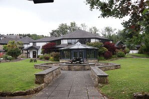 A courtyard with a stone pathway leading to a gazebo, surrounded by greenery and residential buildings. - Hustyns Hotel (Wadebridge)