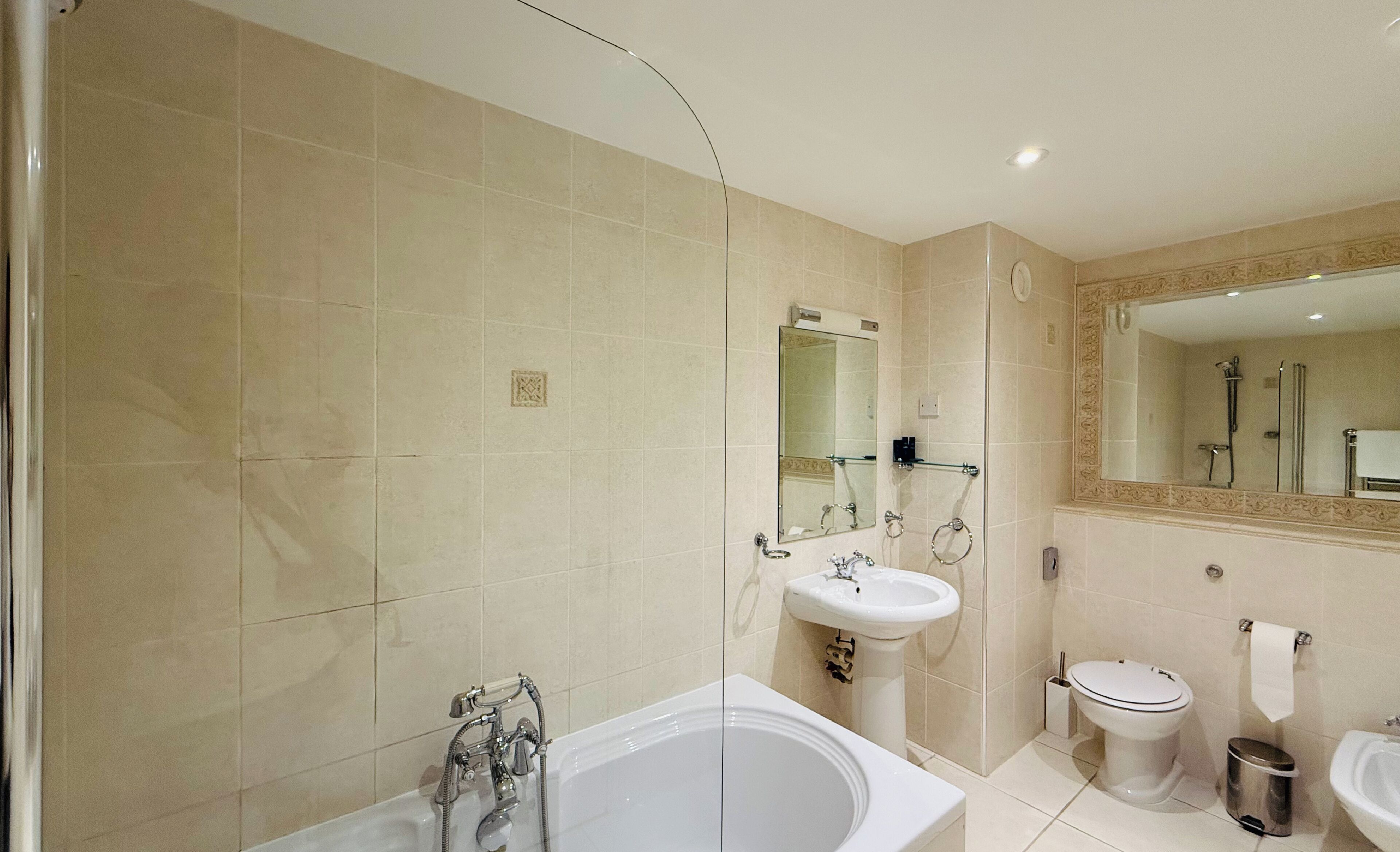 A modern bathroom with a bathtub, sink, toilet, and a large mirror.