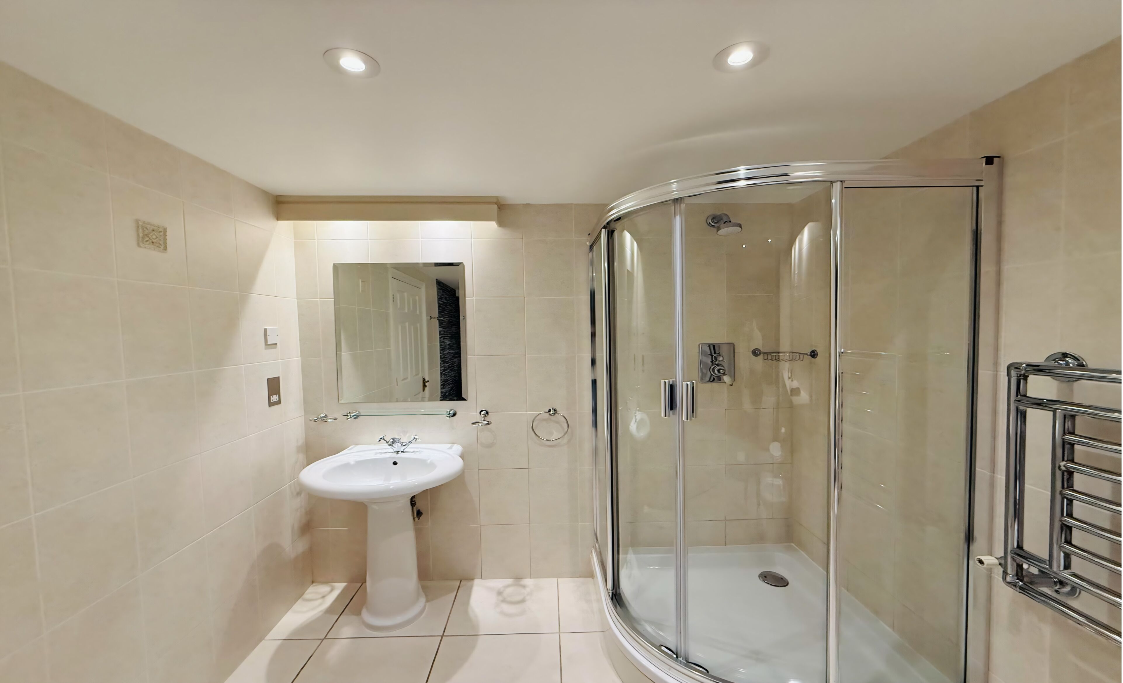 A modern bathroom with a glass-enclosed shower, a pedestal sink, and a mirror.